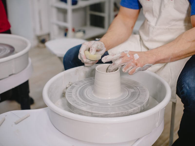 Close up of a person throwing pottery on the wheel